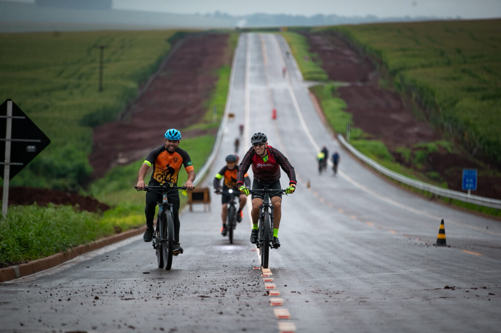 ciclistas andando no asfalto molhado