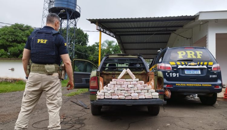 Policial olhando atras de uma caminhonete cheia de tabletes de cocaína embalada