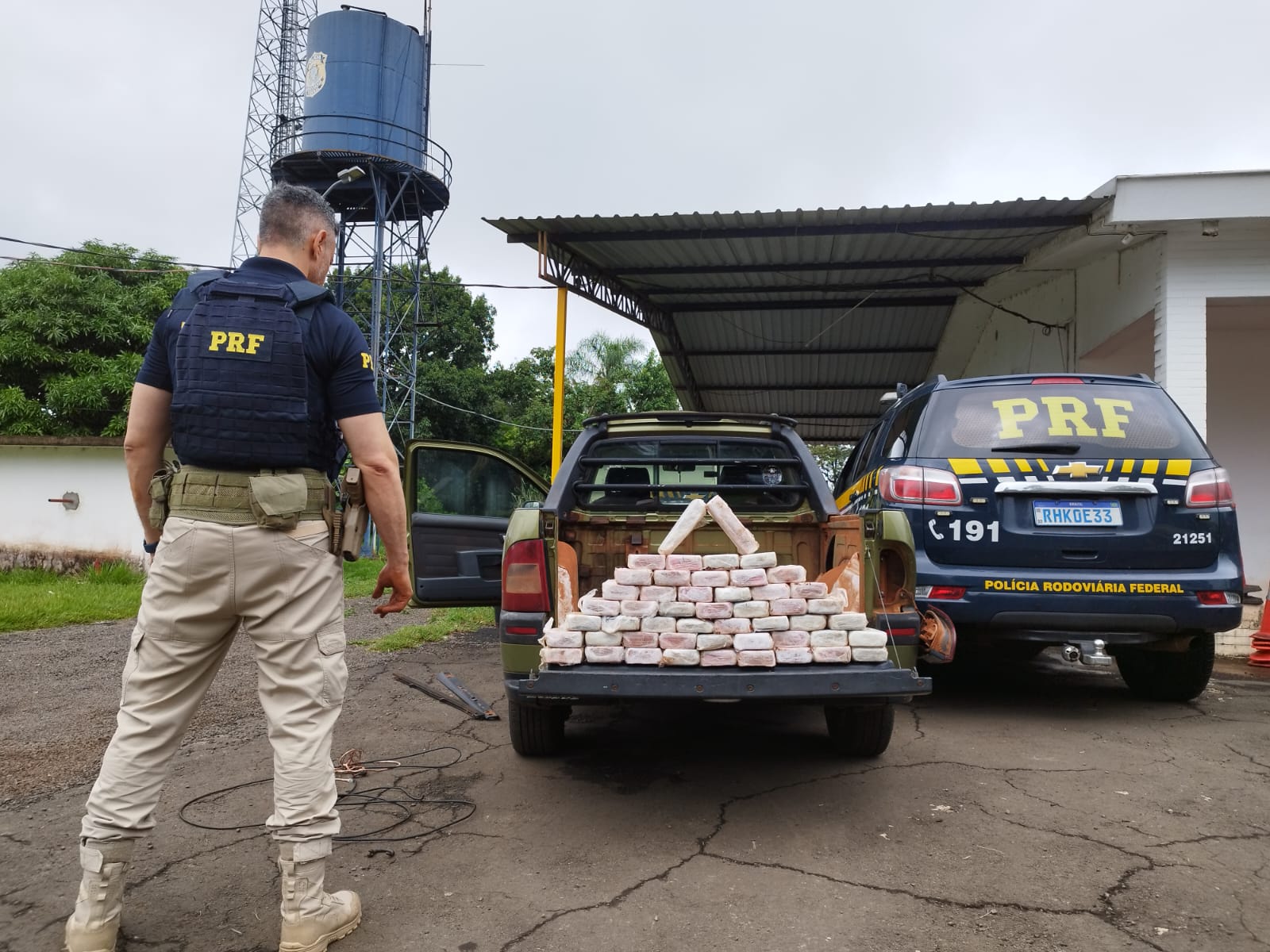 Policial olhando atras de uma caminhonete cheia de tabletes de cocaína embalada